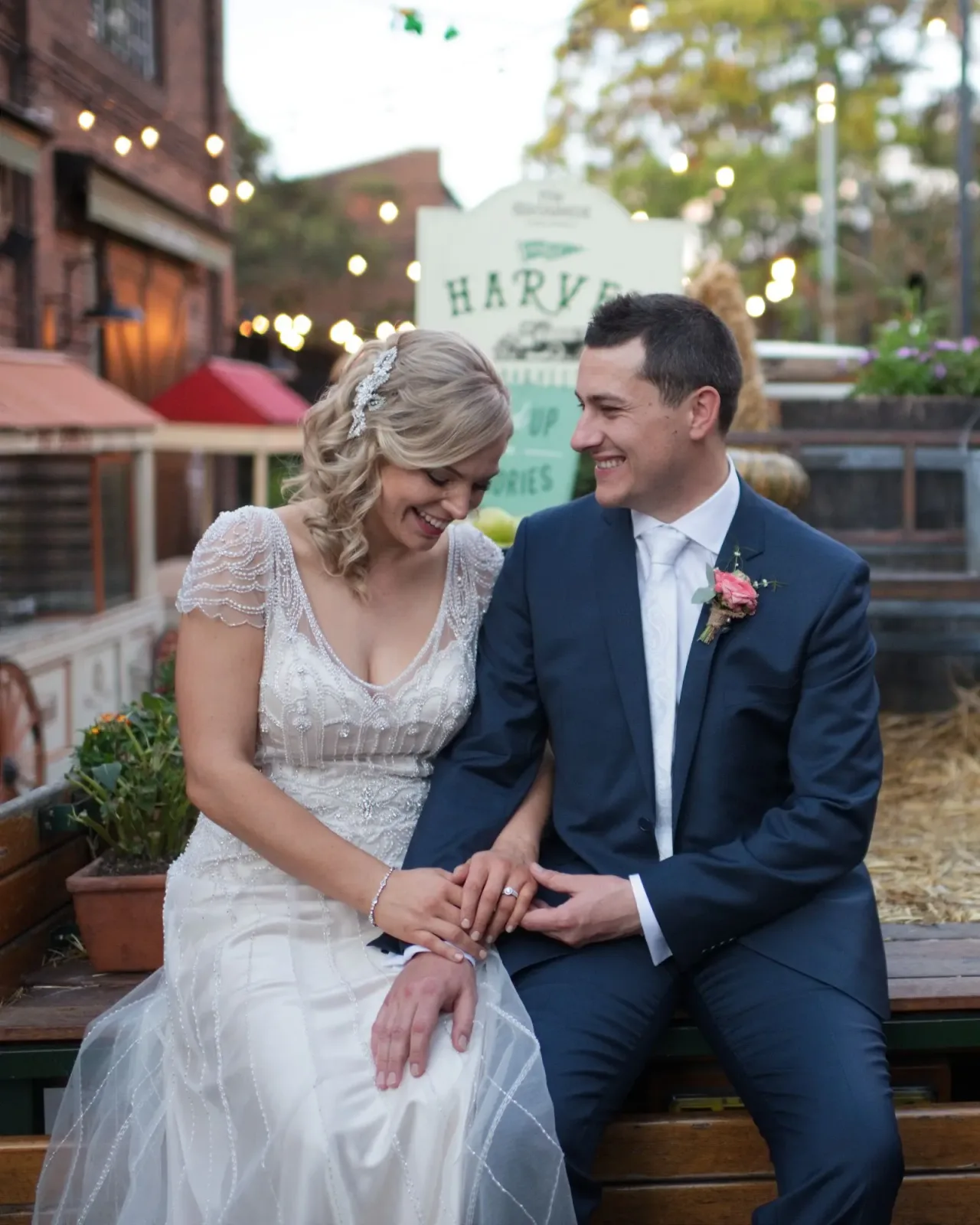 Bride and groom laughing together on a bench under string lights, edited in Lightroom Classic